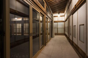 A corridor with sliding glass doors leading to rooms, wooden beams on the ceiling, and a carpeted floor. - Ginrinsou (Otaru)