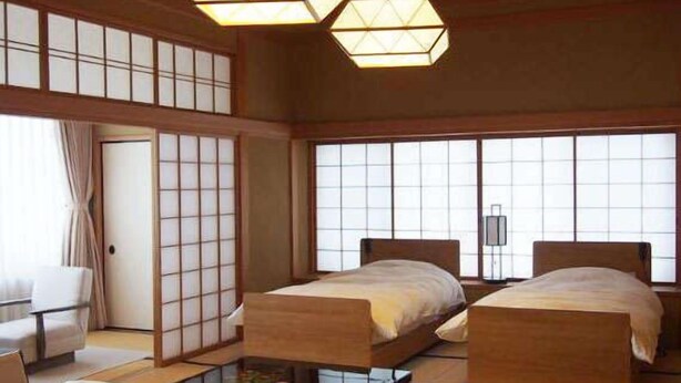 A traditional Japanese-style room with tatami flooring, two wooden beds, a low table, and sliding doors. - Ginrinsou (Otaru)