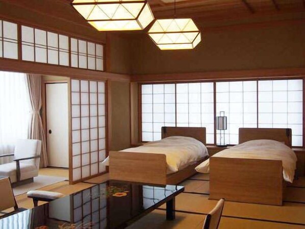 A traditional Japanese-style room with tatami flooring, two wooden beds, a low table, and sliding doors. - Ginrinsou (Otaru)