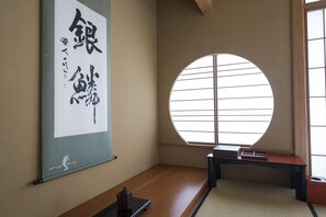 Ein traditioneller japanischer Raum mit Tatami-Boden, Shoji-Schirm und einer Kalligraphie-Aufschrift.