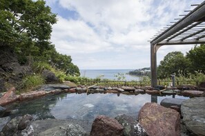 A tranquil outdoor setting with a clear view of the sea, a stone pathway, and a wooden pergola. - Ginrinsou (Otaru)