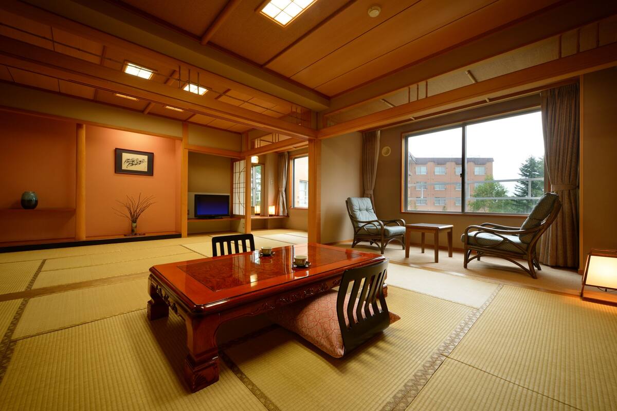 A traditional Japanese-style room with tatami flooring, a wooden table, and two chairs.