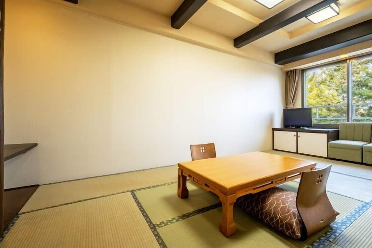 A traditional Japanese room with tatami flooring, a low wooden table, and a sofa by a window.