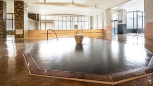 A large indoor swimming pool with a central fountain, surrounded by tiled walls and a wet floor. - Hotel Daiheigen (Otofuke)