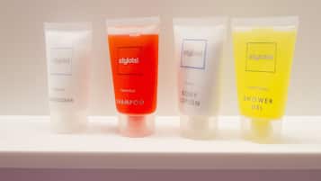 Cuatro tubos de tocador con la etiqueta 'styhotel', con diferentes colores y nombres: 'Acondicionador Impresionante', 'Champú Fabuloso', 'Loción Corporal Refrescante' y 'Gel de Ducha Espléndido'.