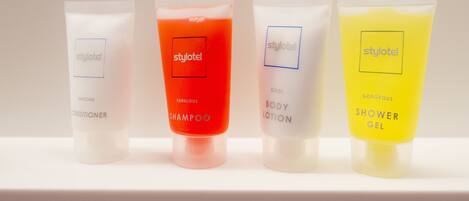Four toiletry tubes labeled 'styhotel' with different colors and names: 'Awesome Conditioner,' 'Fabulous Shampoo,' 'Cool Body Lotion,' and 'Gorgeous Shower Gel.'