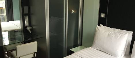 Habitació d'hotel amb llit, escriptori amb cadira, mirall i armari.