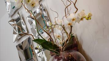 Een vaas met witte orchideeën en een spiegelende wand.