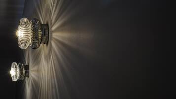 Dues làmpades de paret amb disseny espiral que il·luminen una superfície fosca.