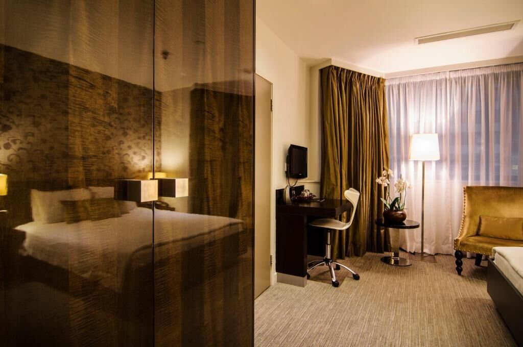 A hotel room with a bed, desk, chair, and a sofa.