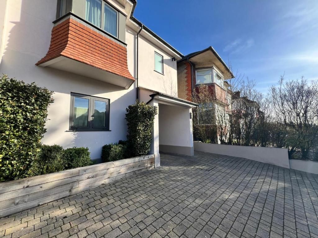 A modern two-story house with a paved driveway and a covered porch.