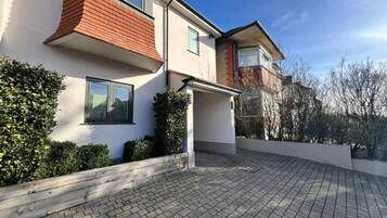 A modern two-story house with a paved driveway and a covered porch.