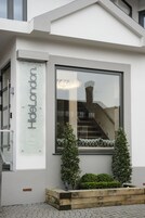 Fachada moderna de un edificio con un gran ventanal, una jardinera de madera con follaje y un cartel que dice "Hidellondon".