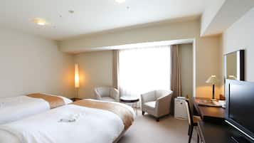 A hotel room with two beds, a desk with a TV, a chair, and a small table.