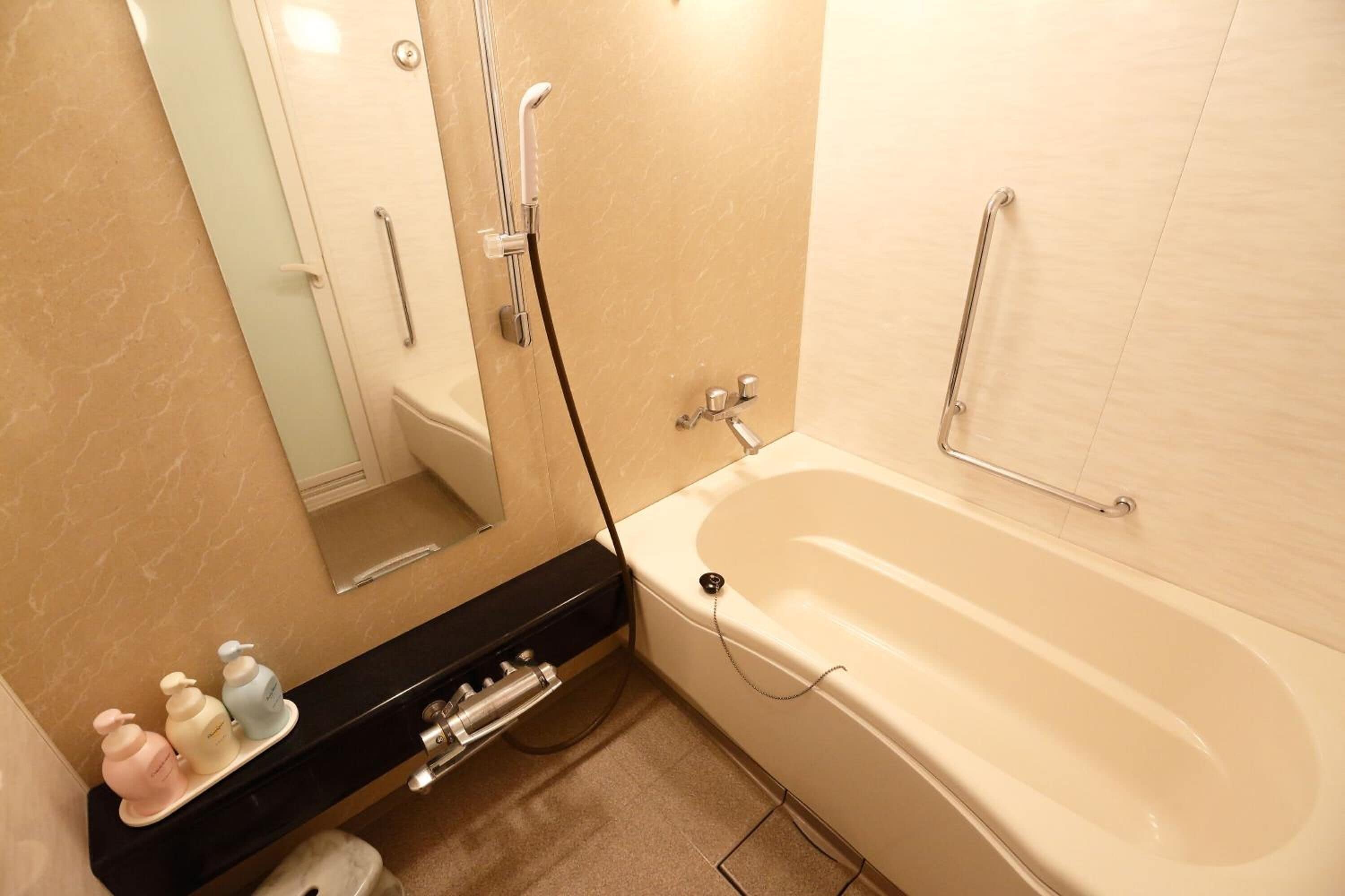 A bathroom with a bathtub, a toilet, a sink with toiletries, and a mirror.