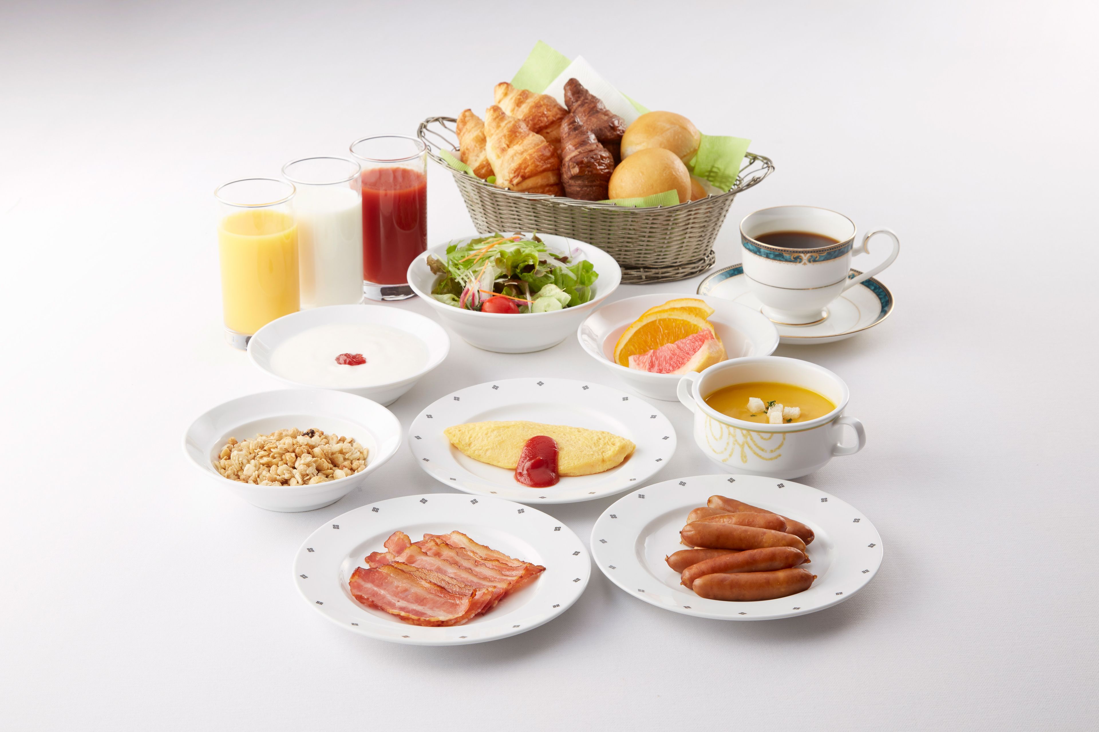 Un'impostazione per la colazione con diversi piatti, tra cui uova, pancetta, salsicce, pane tostato, un'insalata e bevande.