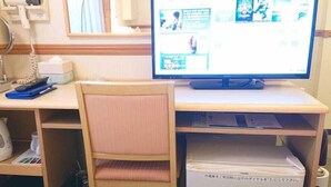 Una habitación con escritorio, computadora, silla y un refrigerador pequeño.