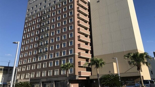 Un hotel de varios pisos con diseño moderno, que combina balcones y ventanas.