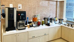 Una cocina moderna con cafetera, dispensador de té y diversos electrodomésticos de cocina.
