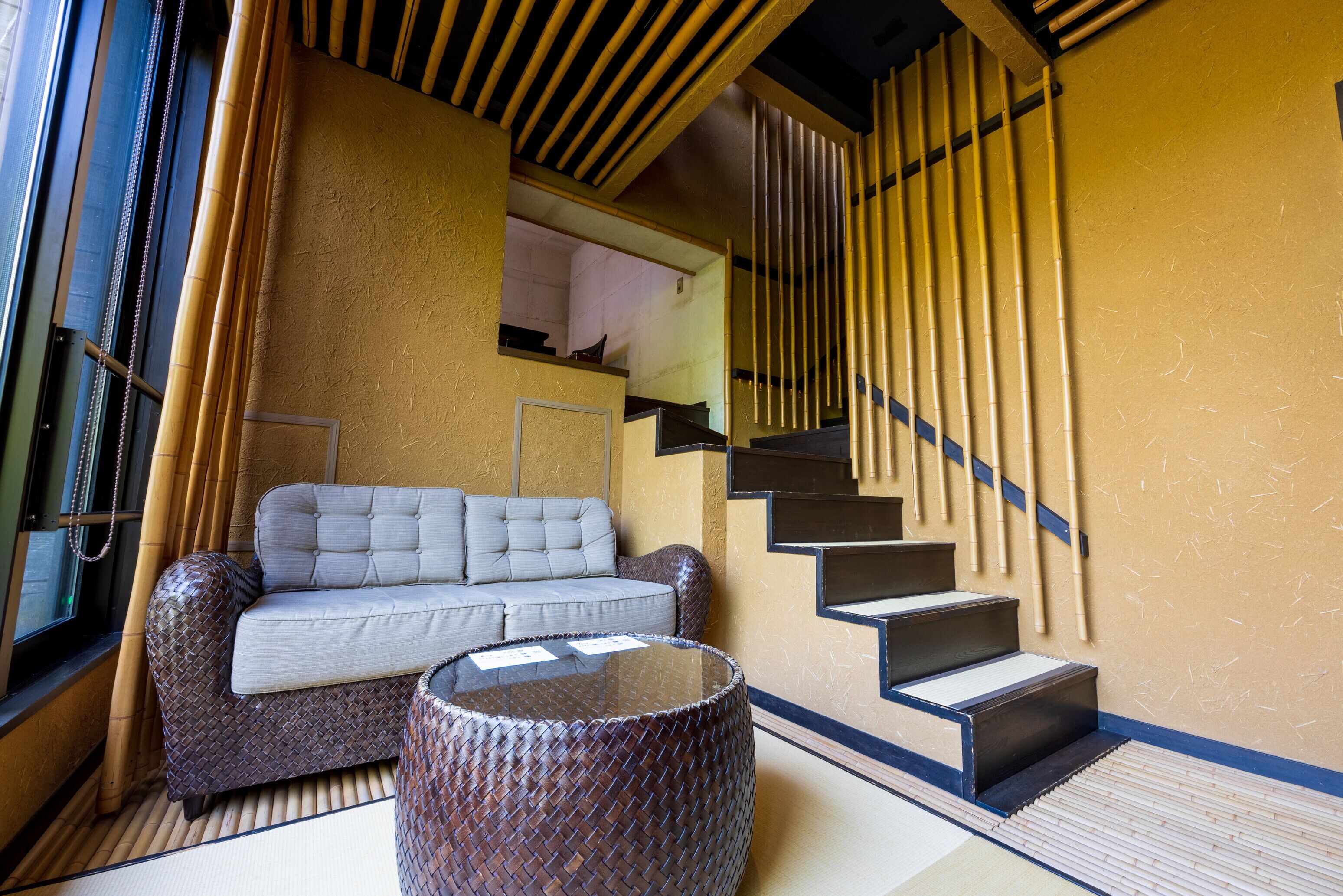 A modern interior with a sofa, a round table, and a staircase with bamboo accents.