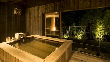 Una bañera de hidromasaje de madera con vistas a un balcón y árboles.