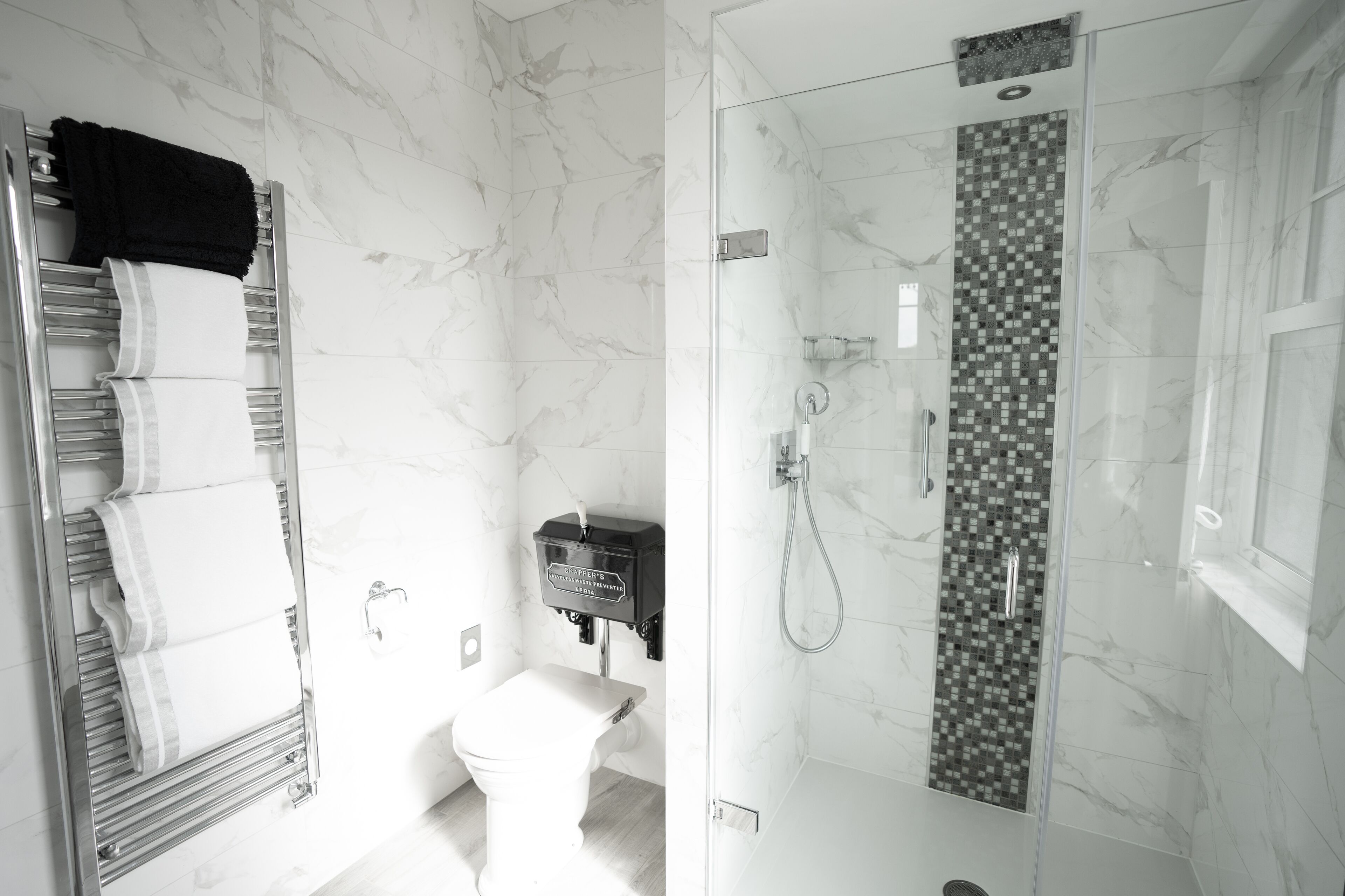 Une salle de bain moderne avec une douche à parois de verre, des toilettes et un porte-serviettes où sont soigneusement pliées les serviettes.