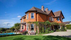 A large brick house with a swimming pool, surrounded by a well-maintained lawn and garden. - The Dower House Hotel (Lyme Regis)