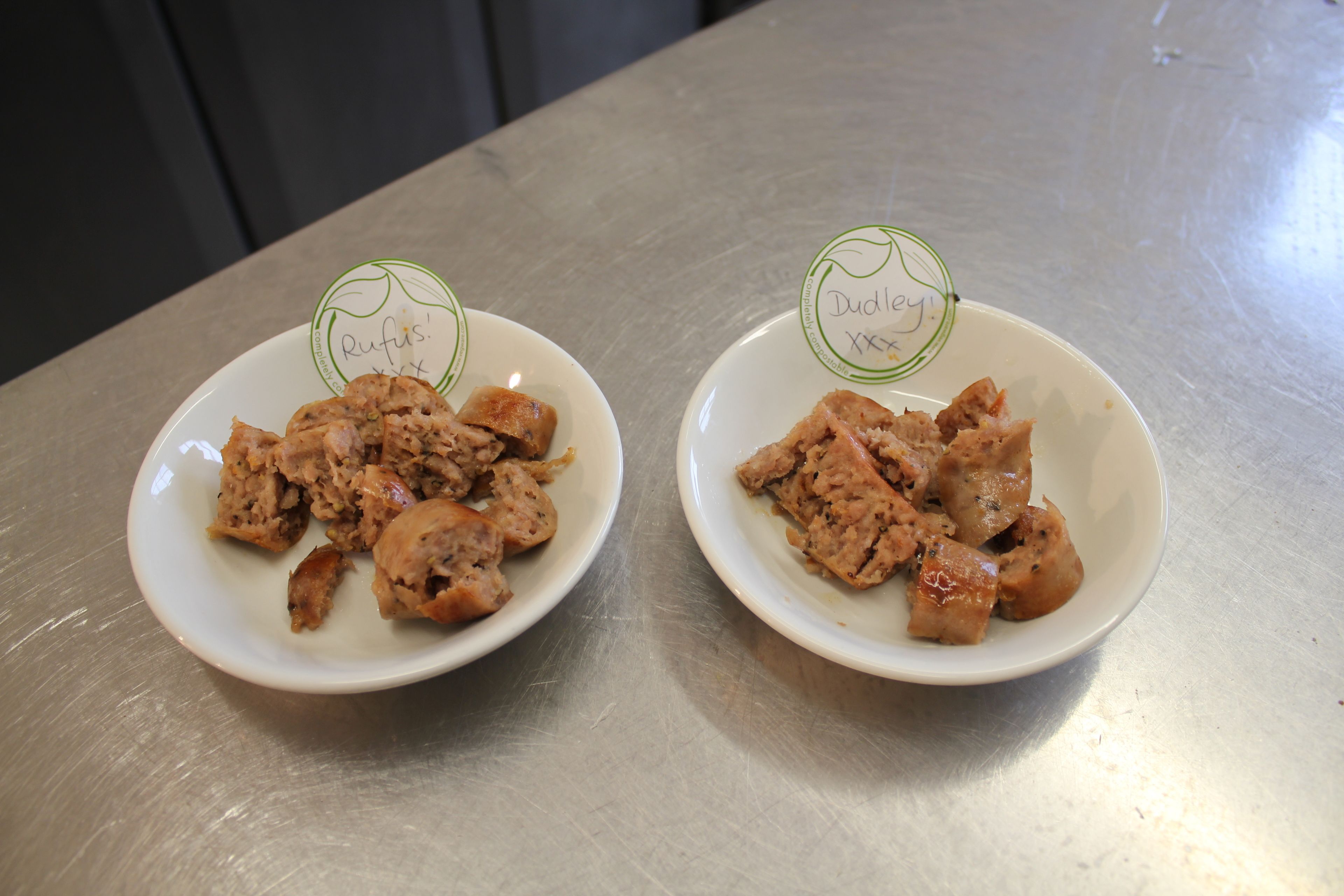 Two white plates with food on a stainless steel table.