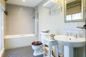 Een bad/douchecombinatie, een haardroger, handdoeken