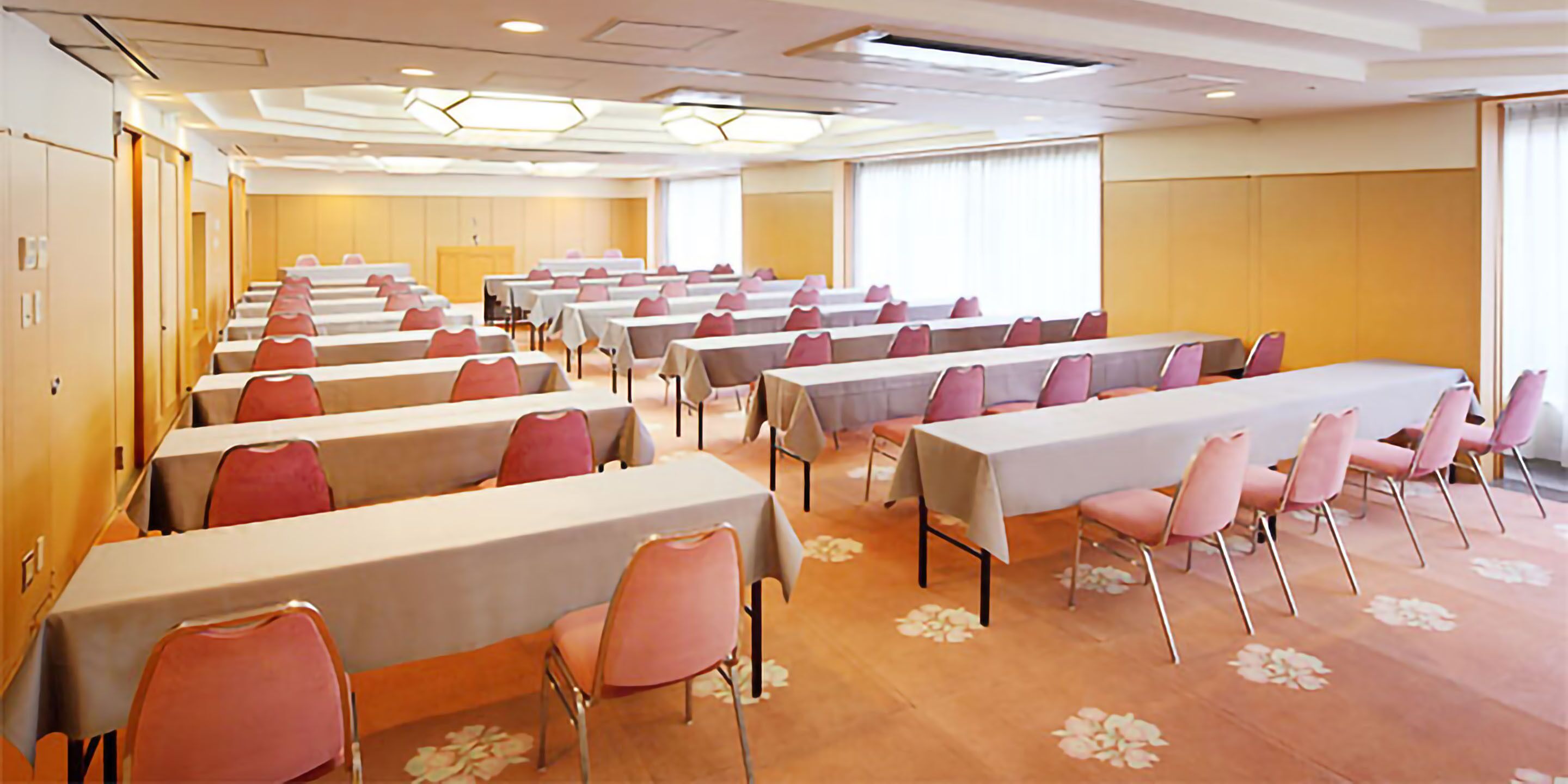 A conference room with multiple tables and chairs, arranged in rows.