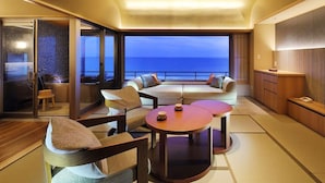 A modern interior with a sofa set, a TV, and a view of the ocean. - Kamogawakan (Kamogawa)