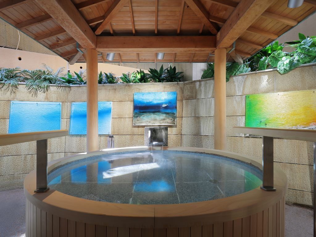 A hot tub area with a wooden ceiling, stone walls, and artwork.
