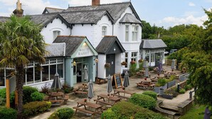 A traditional white building with a sign reading "The White Rabbit" and a patio area with wooden tables and umbrellas. - White Rabbit Hotel by Chef and Brewer Collection (Lyndhurst)