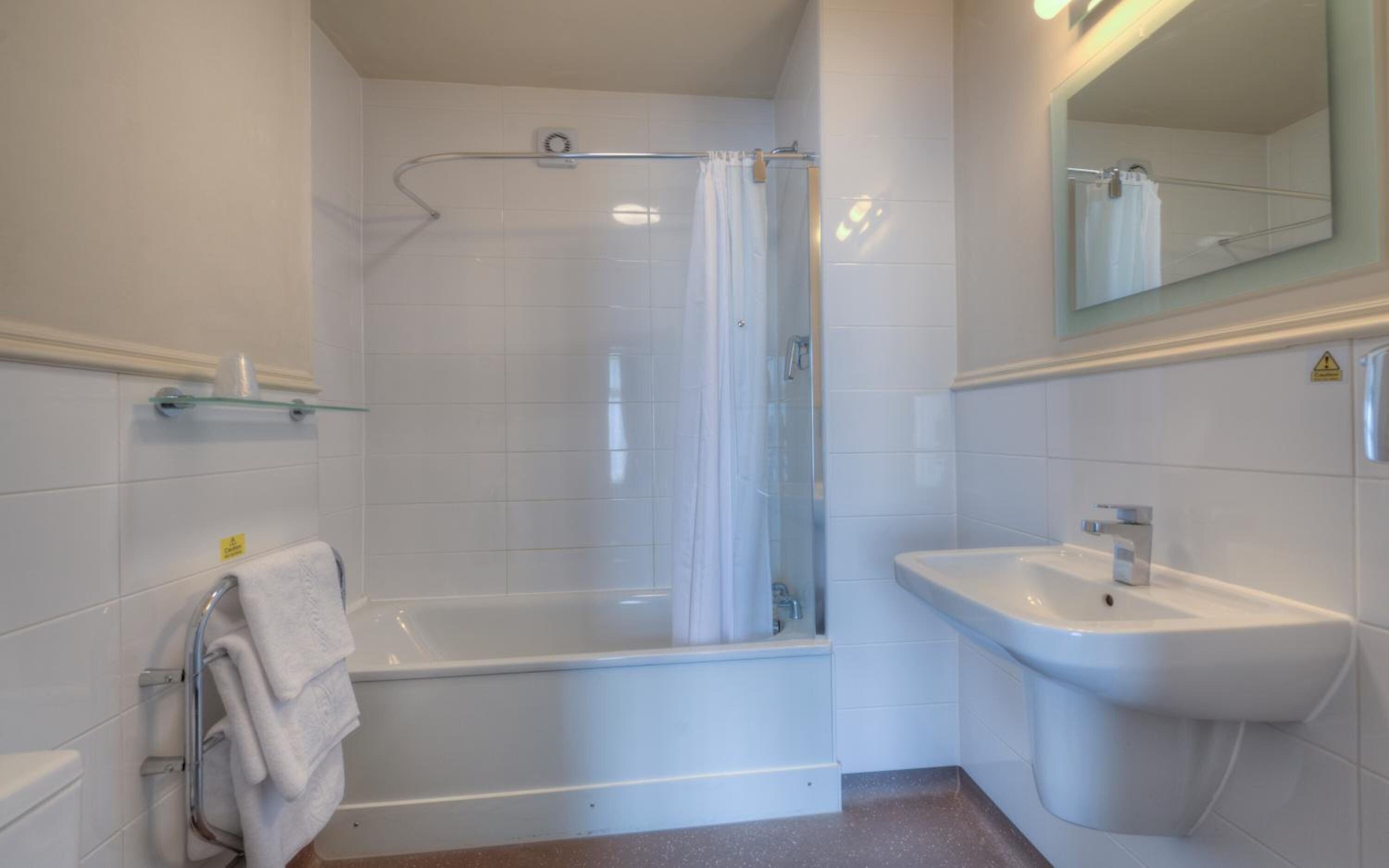 A modern bathroom with a shower, bathtub, and sink.