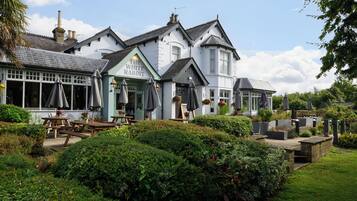 A traditional pub with outdoor seating, a well-maintained garden, and a classic architectural style.