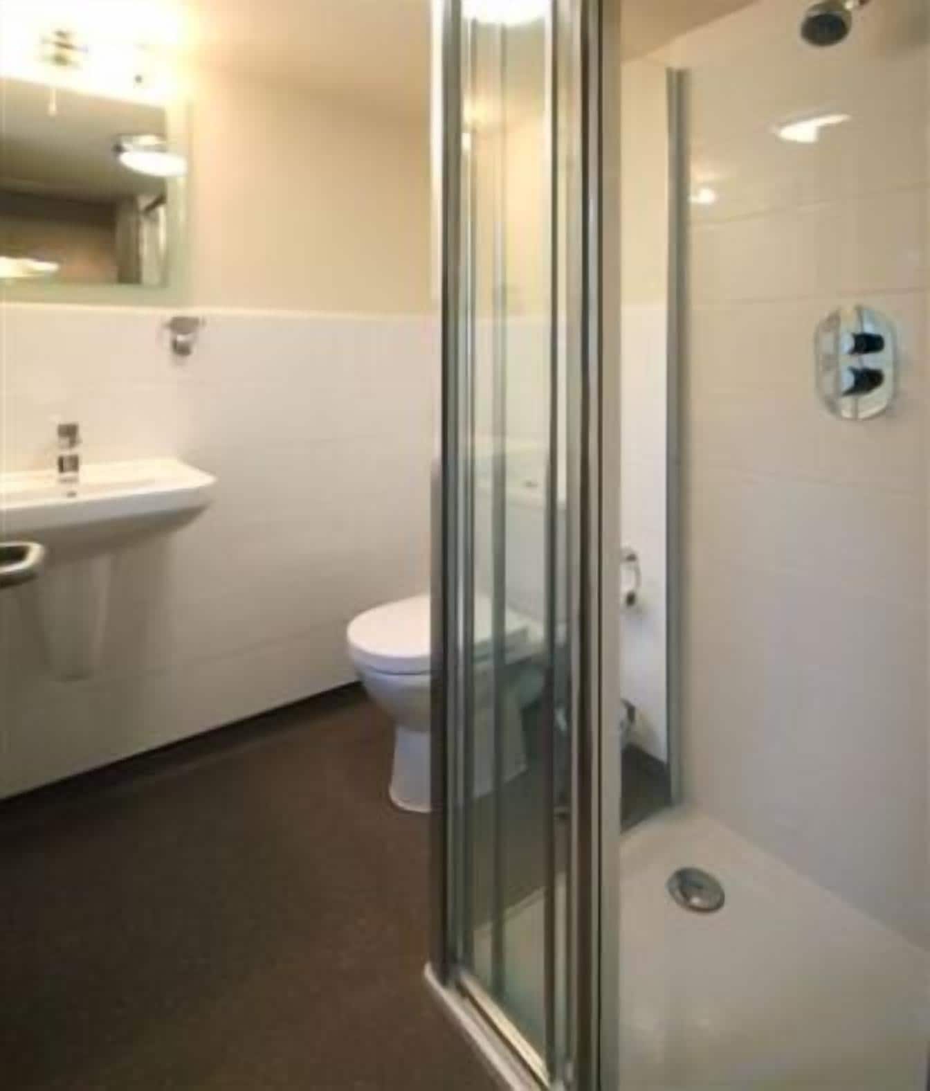 Une salle de bain avec une douche à parois de verre, des toilettes et un lavabo.