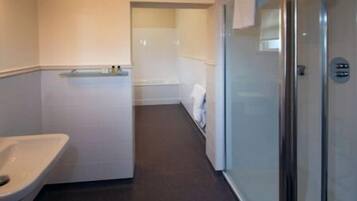 A bathroom with a toilet, a shower, and a glass-enclosed shower area.