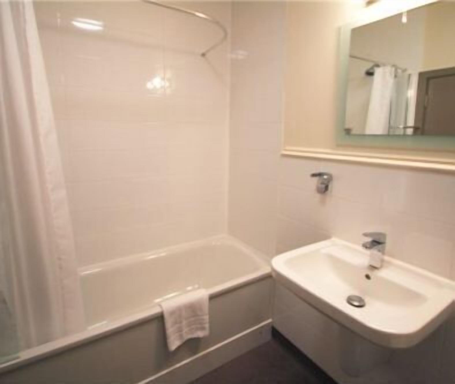 A bathroom with a bathtub, a sink, and a mirror.