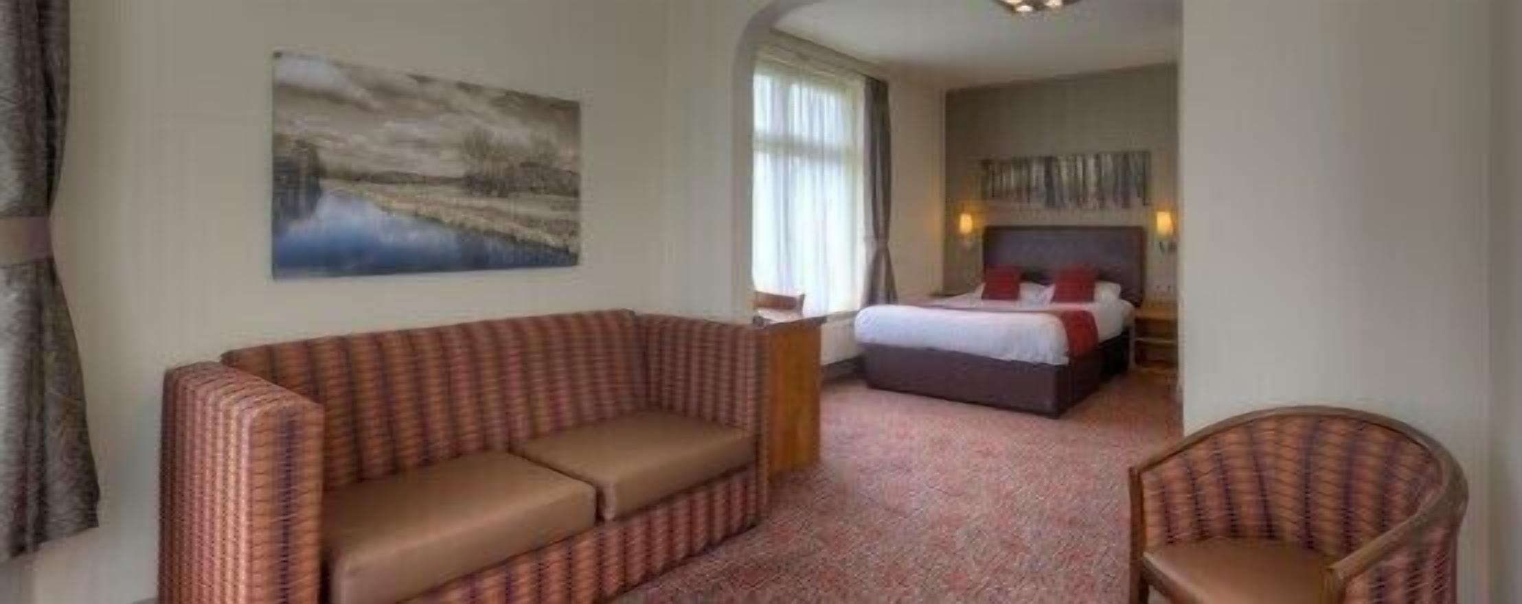 Une chambre d’hôtel avec un lit, un canapé et un fauteuil.