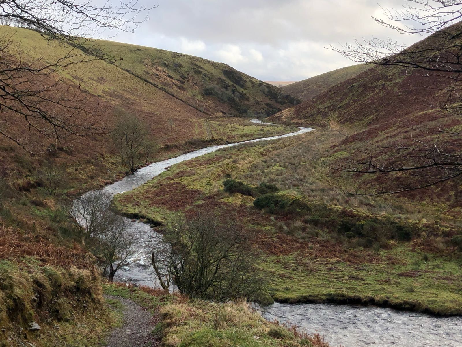 Une rivière serpente à travers une vallée, avec des collines de chaque côté.