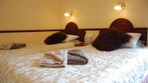 A hotel room with two beds, each with a wooden headboard, a patterned bedspread, and a pair of towels on the bed. - The Hollingworth (Lytham St. Anne's)