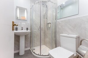A modern bathroom with a glass-enclosed shower, a pedestal sink, and a toilet. - The Hollingworth (Lytham St. Anne's)