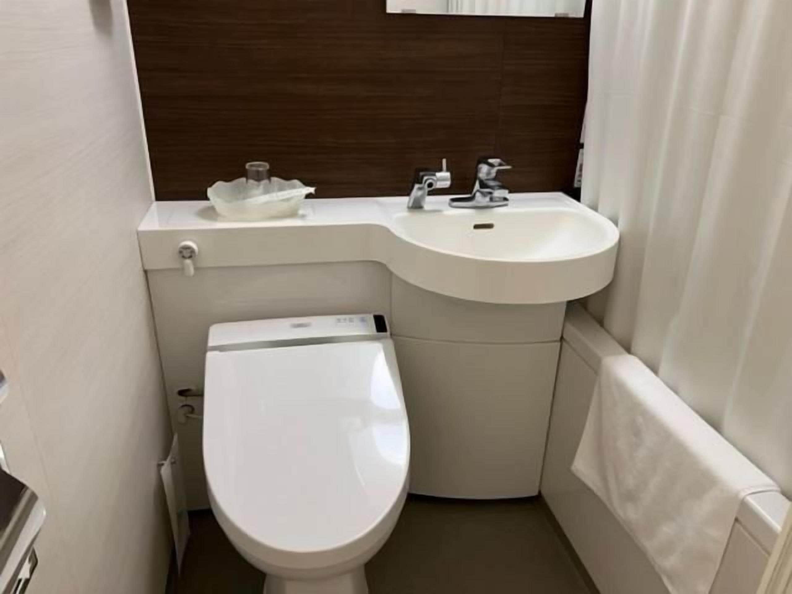 A compact bathroom with a toilet, sink, and a small storage area.