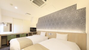 A hotel room with two beds, a desk with a flat-screen TV, a mirror, and a patterned wall. - Hotel Shinjukuya (Machida)