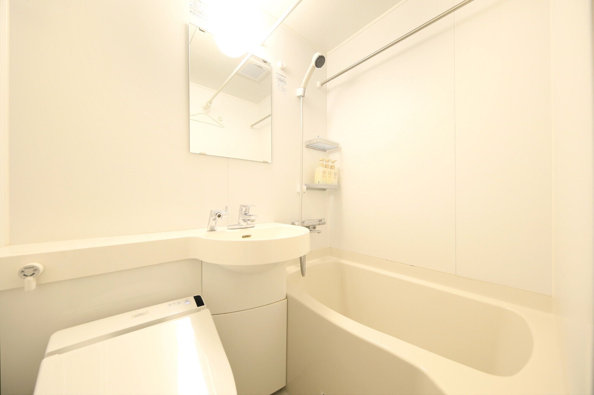 A bathroom with a white sink, a mirror, a shower, and a toilet.