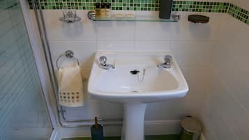 A bathroom with a white sink, a glass shelf with toiletries, and a towel rack.