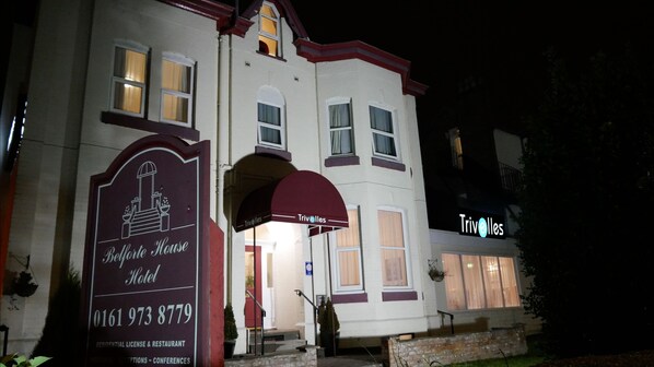 A hotel named 'Belle House Hotel' with a signboard displaying the name and contact number.