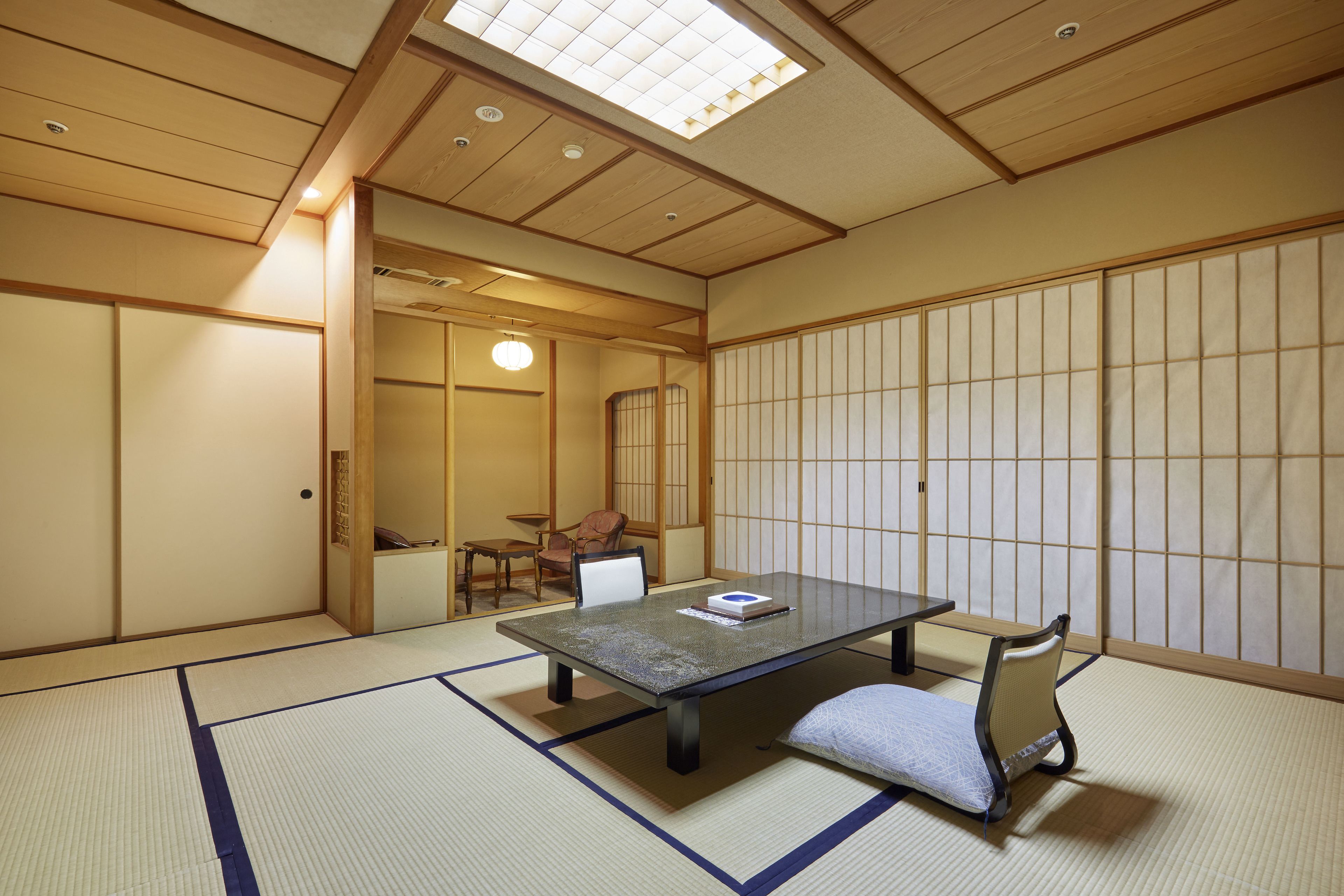 Une pièce de style japonais traditionnel, avec un sol recouvert de tatamis, une table basse et une chaise.