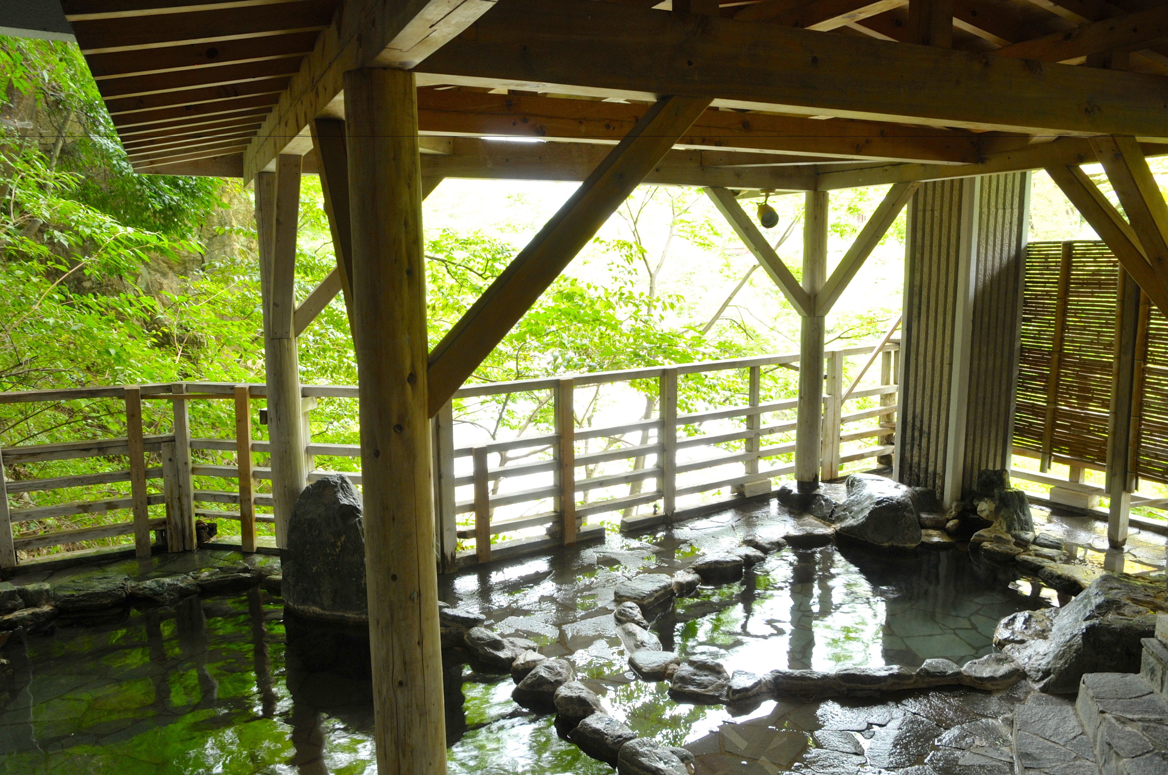 Eine traditionelle Holzhütte mit Teich aus Stein und Holzgeländern.