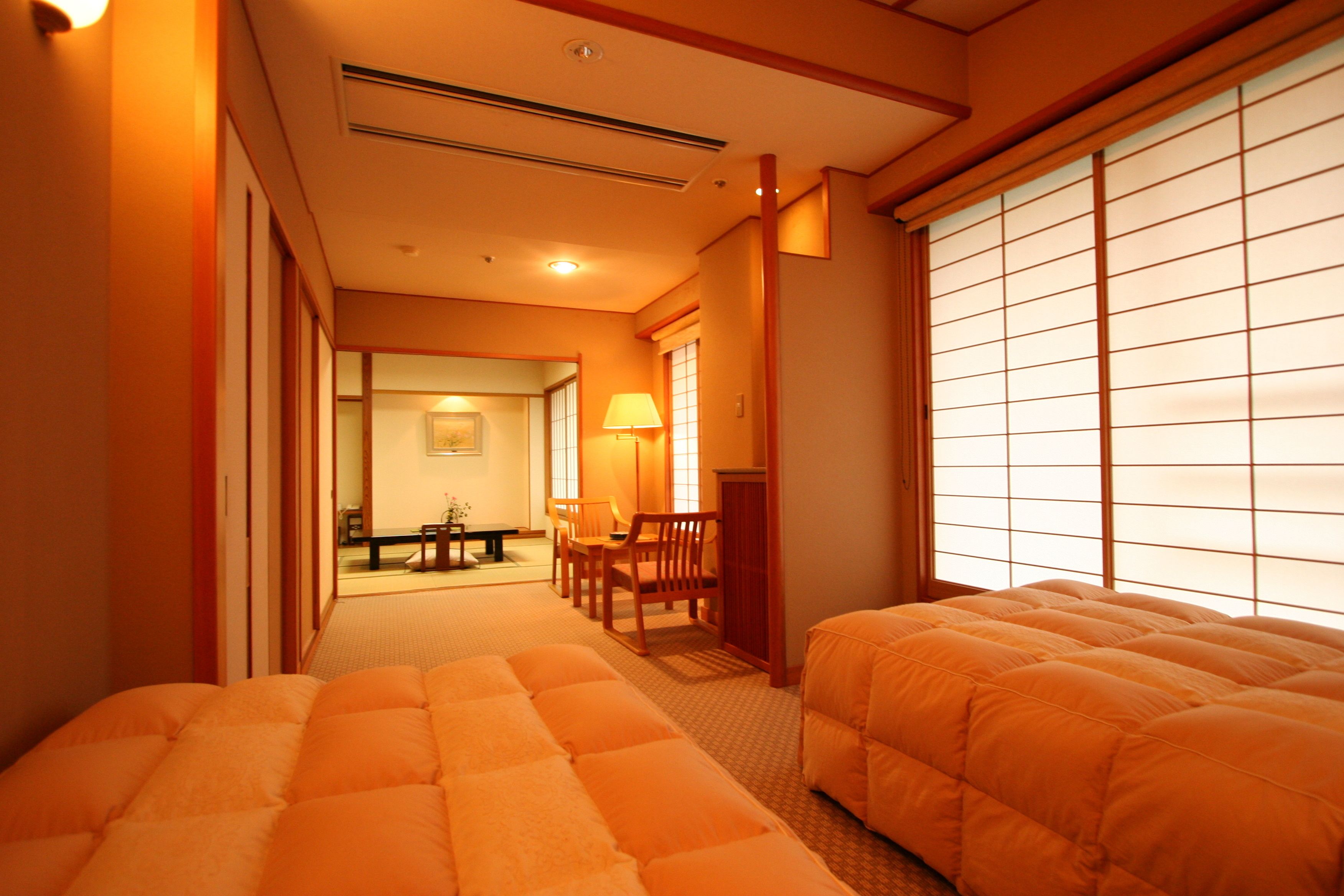 A hotel room with two beds, a dining area, and a sliding shoji screen.